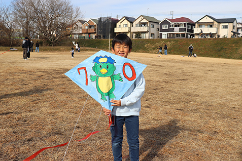 自分で描いた凧を手にほほえむ子どもの写真