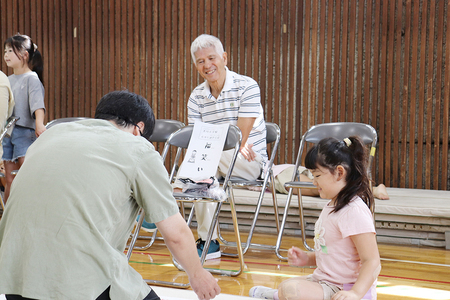 親子が遊ぶのを見守る安芸さんの写真